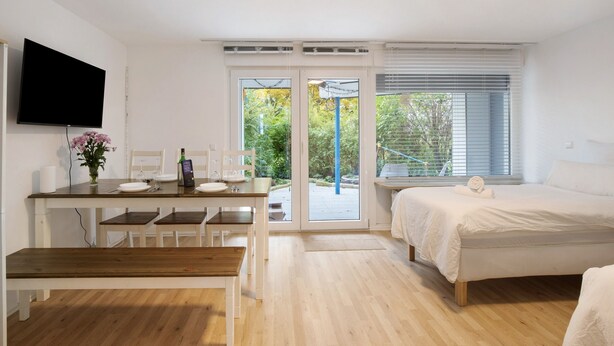 Un dormitorio con cama, un escritorio con computadora y televisor.