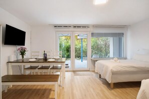 A bedroom with a bed, a desk with a computer, and a TV.