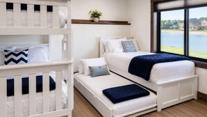 Un dormitorio con literas, una cama individual, una ventana con vistas a un cuerpo de agua y un estante pequeño con una planta.