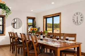 A dining area with a wooden table, chairs, a clock, and a window with a view.