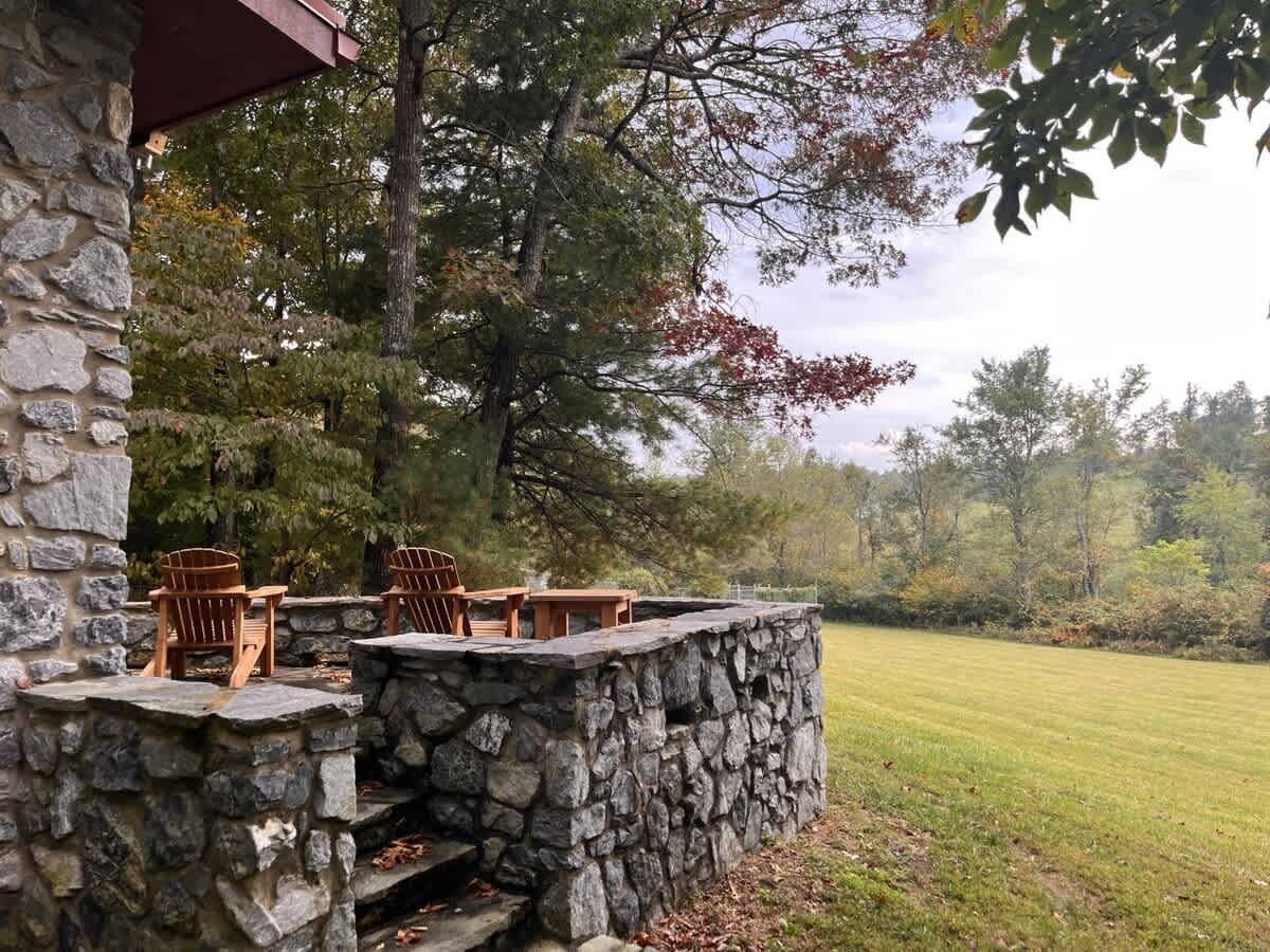 A stone patio with Adirondack chairs and a stone wall.
