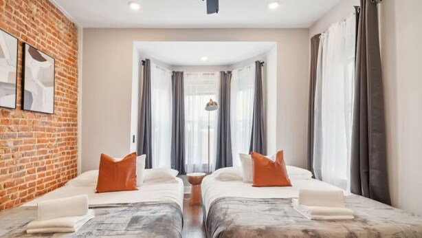 Een hotelkamer met twee bedden, een bakstenen muur en uitzicht op de straat.