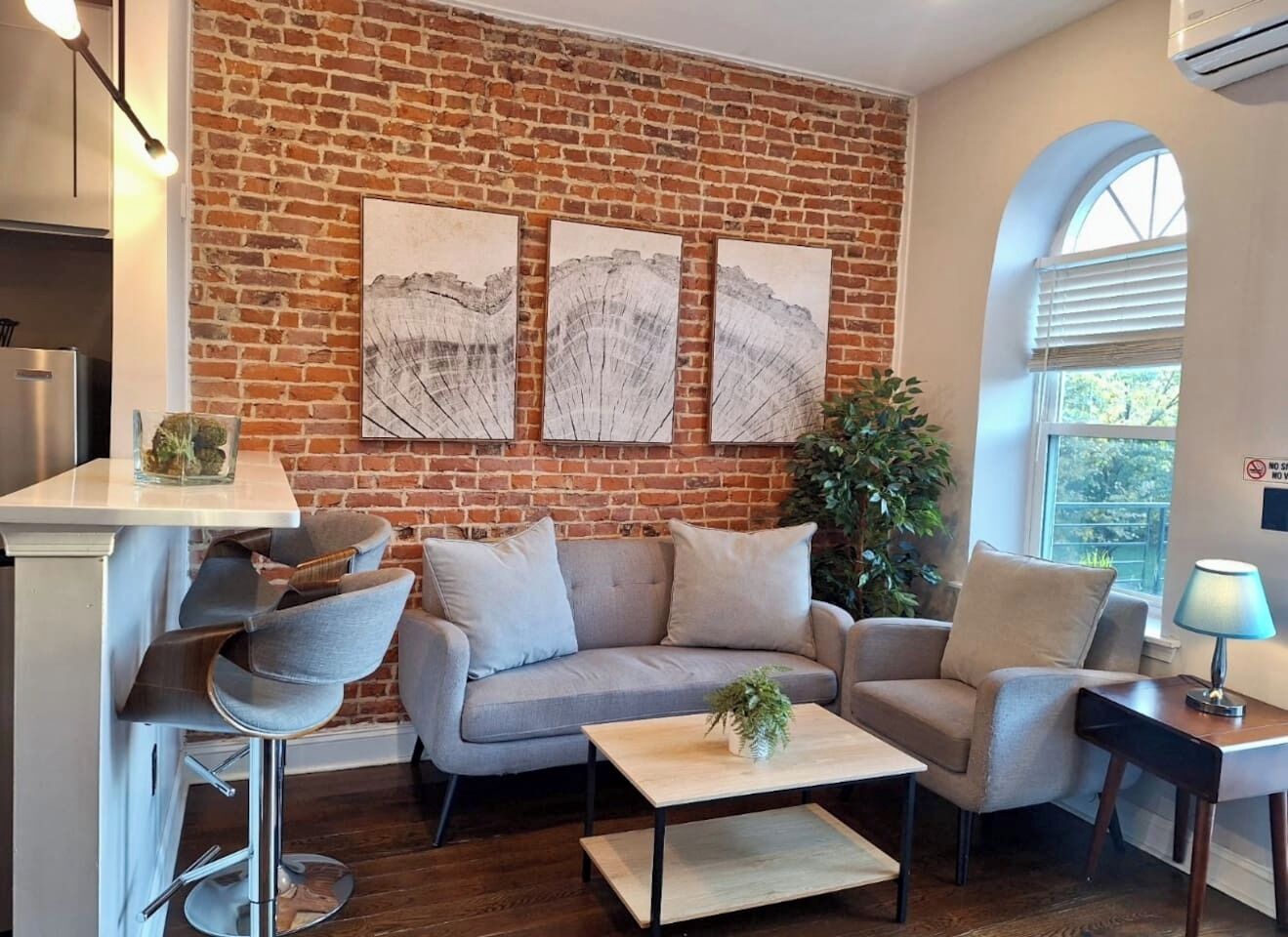 Un salon avec un mur en briques, un canapé, une table basse et une plante.