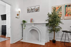 Una habitación con chimenea blanca, televisor de pantalla plana y cuadros en la pared.