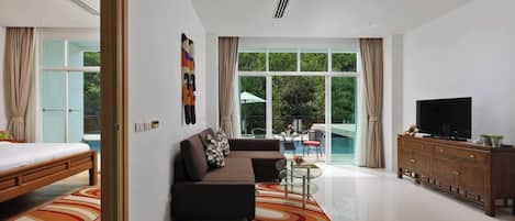 A modern hotel room with a bed, sofa, TV, and a view of a swimming pool.