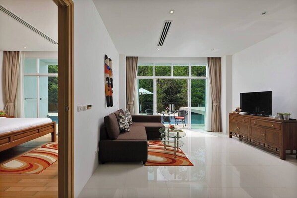 A modern hotel room with a bed, sofa, TV, and a view of a swimming pool.