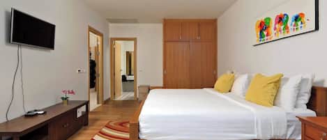 A bedroom with a bed, wooden wardrobe, television, and a painting on the wall.