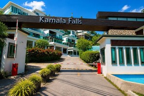 Een hek afsluit de ingang naar Kamala Falls, met een modern gebouwcomplex op de achtergrond.