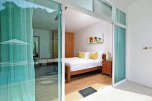 A bedroom with a bed, bedside table, and a wall-mounted artwork.