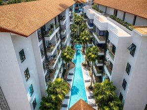 A multi-story hotel with a central swimming pool surrounded by balconies and palm trees.