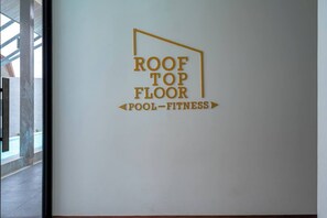 A sign indicating the location of the roof top floor, which includes a pool and fitness facilities.