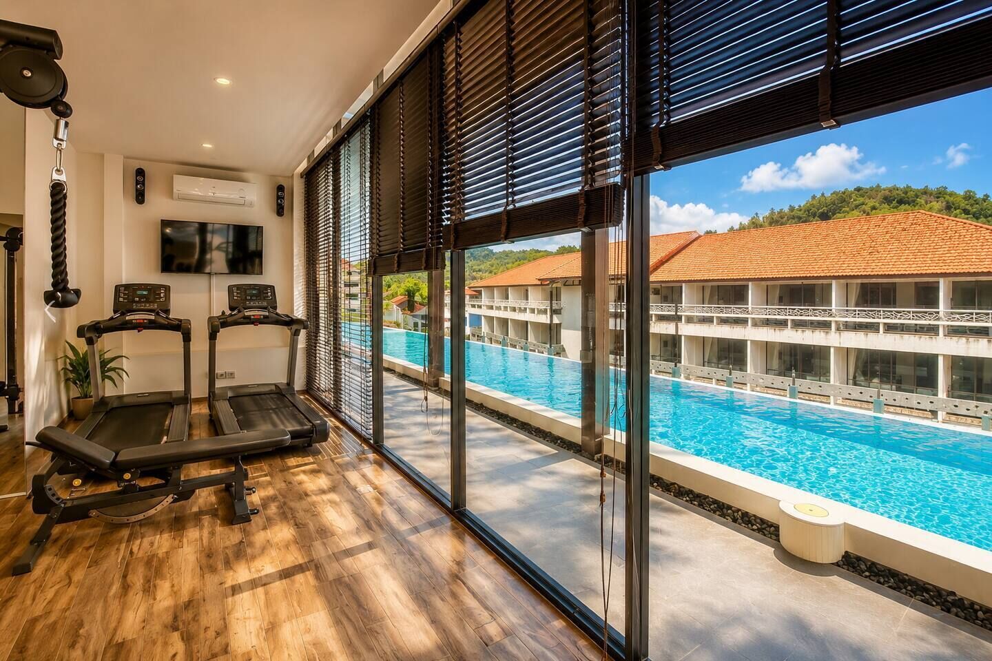 Ein Hotelzimmer mit Laufband, Fernseher und Blick auf ein Schwimmbad.