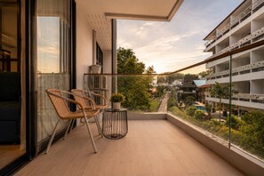 Un balcon avec des fauteuils en osier, une petite table et une plante en pot.