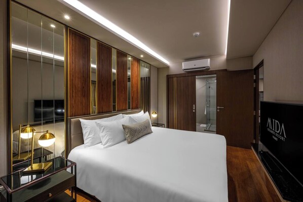 A hotel room with a large bed, a TV, a mirror, a wardrobe, and a shower.