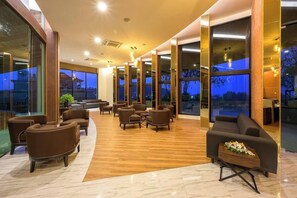 A spacious indoor area with multiple seating arrangements, large windows, and a wooden floor. - Suite Calista 2br|view & Jacuzzi|mida grande surin (Choeng Thale)