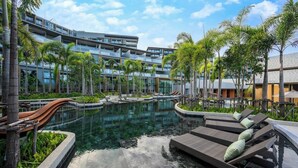 Um resort com piscina, espreguiçadeiras e um edifício moderno com varandas.