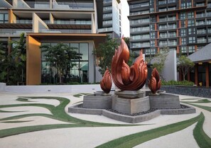 Un bâtiment moderne doté d’une cour aménagée avec une sculpture centrale.
