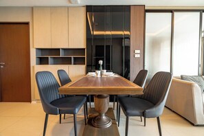 Un espace repas moderne avec une table en bois, des chaises noires et un meuble de cuisine intégré.