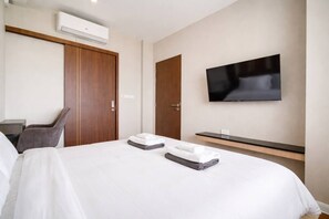 A hotel room with a bed, a TV mounted on the wall, a desk, and a chair. - Suite Calista 2br|view & Jacuzzi|mida grande surin (Choeng Thale)