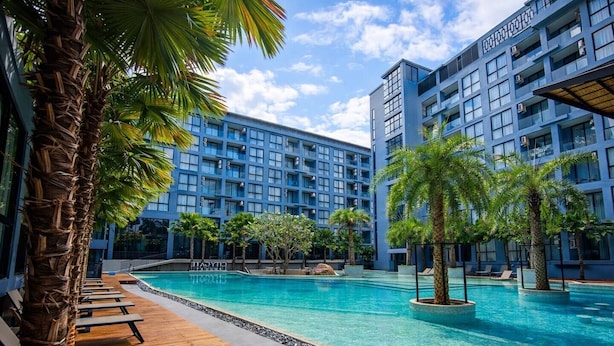Um hotel com piscina, rodeado por palmeiras e espreguiçadeiras.