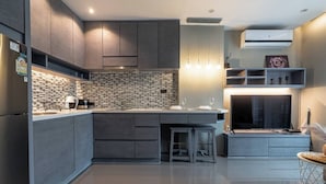 Uma cozinha moderna com ilha central, eletrodomésticos embutidos e uma TV de tela plana.