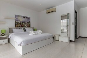 A modern hotel room with a large bed, a bedside table, a nightstand, a mirror, and a painting on the wall.