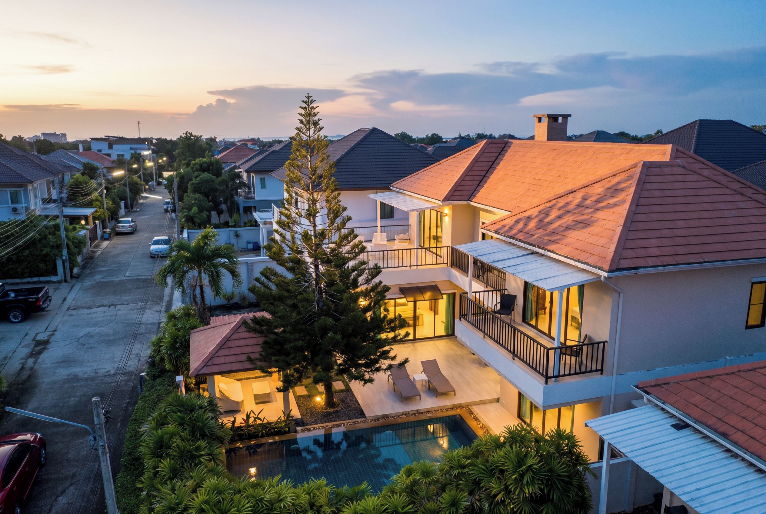 Un quartier résidentiel avec des maisons, une piscine et un grand arbre.