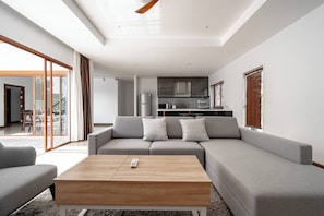 A modern living room with a grey sofa, a wooden coffee table, and a remote control on it.