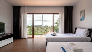 Habitación de hotel con balcón, cama, televisor y escritorio.