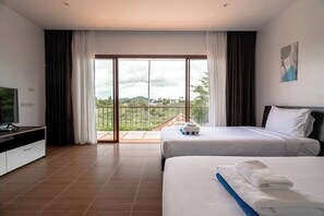 A hotel room with a balcony, a bed, a TV, and a desk.