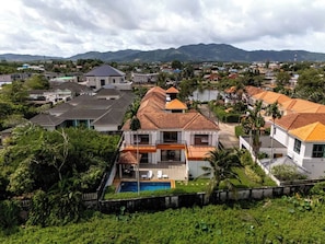 Un quartier résidentiel avec des maisons, une piscine et un paysage montagneux en arrière-plan.