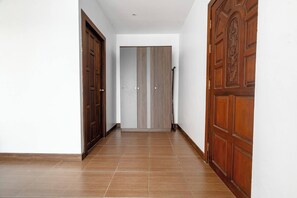 Un couloir avec deux portes en bois, une de chaque côté, et une porte centrale ornée d’un panneau vertical.
