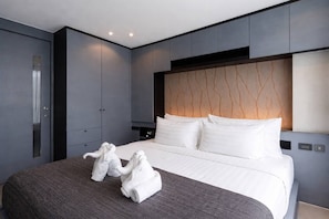 A modern hotel room with a large bed, grey walls, and a unique patterned headboard. - Suite Zenith 1br|rooftop Pool &bar|citygate kamala (Tambon Kammala)