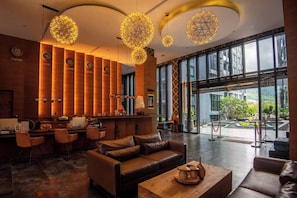 Een moderne lobby met lederen zitplaatsen, een receptiebalie en grote ramen met uitzicht op het omliggende landschap.