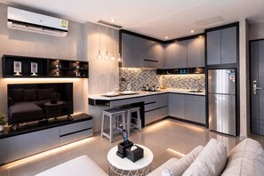 Een moderne keuken met een centraal eiland, inbouwapparatuur en een zithoek met een bank en barkrukken.