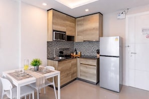 A compact kitchen with a refrigerator, microwave, and a tiled backsplash. - Suite Maris 1br |sea View| rawai (Rawai)
