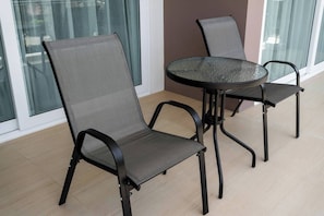 A dining area with a round table and two chairs, a glass partition, and a view of the outside.