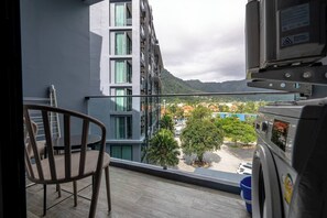A balcony with a chair, a view of a residential area, and a parked vehicle.