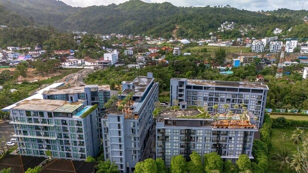 Un edificio moderno a più piani con tetto piano, immerso nel verde e circondato da altri edifici residenziali.