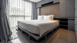 Una camera da letto moderna con un letto grande, scaffali a muro e vista sul verde.