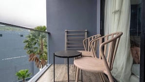 Un balcone con tavolo e sedie, un portasciugamani e vista su un edificio con palme.