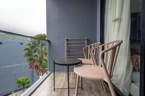 A balcony with a table and chairs, a towel rack, and a view of a building with palm trees.