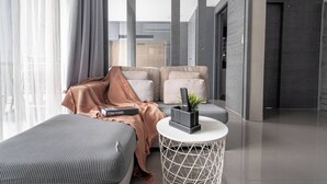 Una habitació d'hotel moderna amb un sofà, una taula rodona petita amb una planta, i un llibre al sofà.