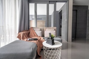 A modern hotel room with a sofa, a small round table with a plant, and a book on the sofa.