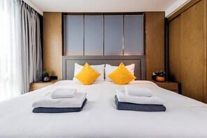A hotel room with a large bed, two nightstands, and a wooden headboard. - Suite Elio 1br | Pools|gym & shuttle to nai harn (Rawai)