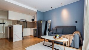 Um apartamento moderno com cozinha, sala de jantar e sala de estar, incluindo sofá e televisão.