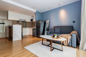 A modern apartment with a kitchen, a dining area, and a living room with a sofa and a TV.