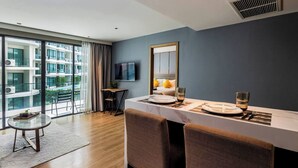 Quarto de hotel moderno com área de refeições, uma grande janela com vista para a cidade, televisão de tela plana na parede e um respiradouro no teto.