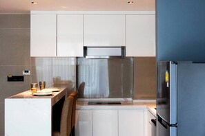 A modern kitchen with white cabinetry, a stainless steel range hood, and a built-in refrigerator. - Suite Elio 1br | Pools|gym & shuttle to nai harn (Rawai)
