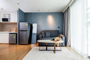 A modern living space with a kitchen, a sofa, and a coffee table. - Suite Elio 1br | Pools|gym & shuttle to nai harn (Rawai)